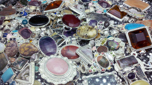 A mound of beautifully mounted gemstones in sterling silver bezels made into pendants