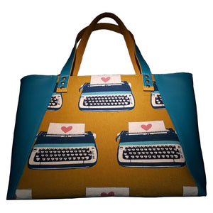 Be Still My Heart Tote Bag, front view of mustard canvas fabric with typewriters and hearts and side panels in teal faux leather, by just.a.tad accessories, sold by Gems from Paradise.