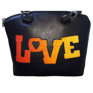 LOVE is appliqued in orange-red to yellow on the front of this black vinyl bag by just.a.tad accessories, sold by Gems from Paradise.